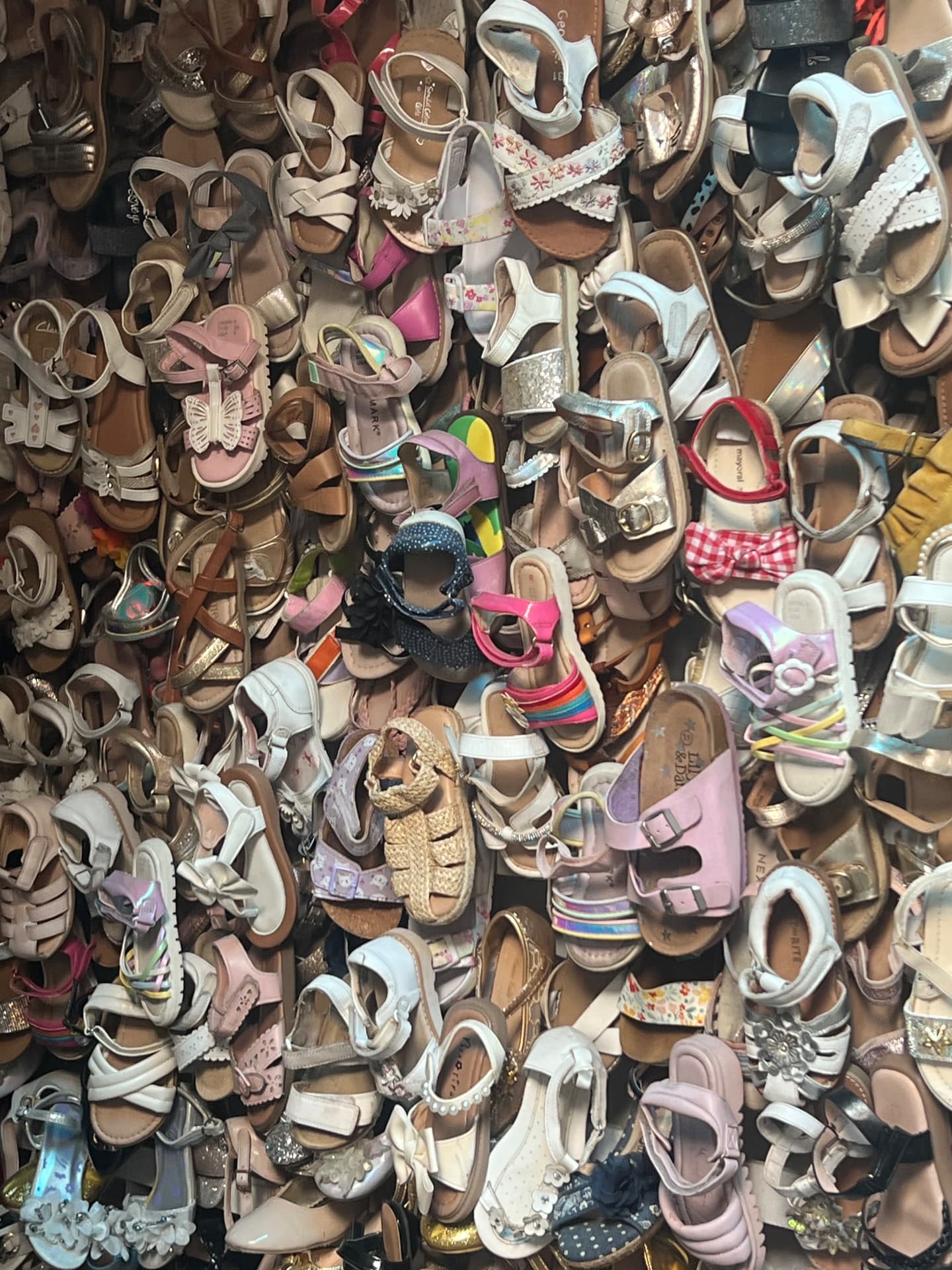 A dense wall of imported second-hand children's sandals for sale at Kantamanto.