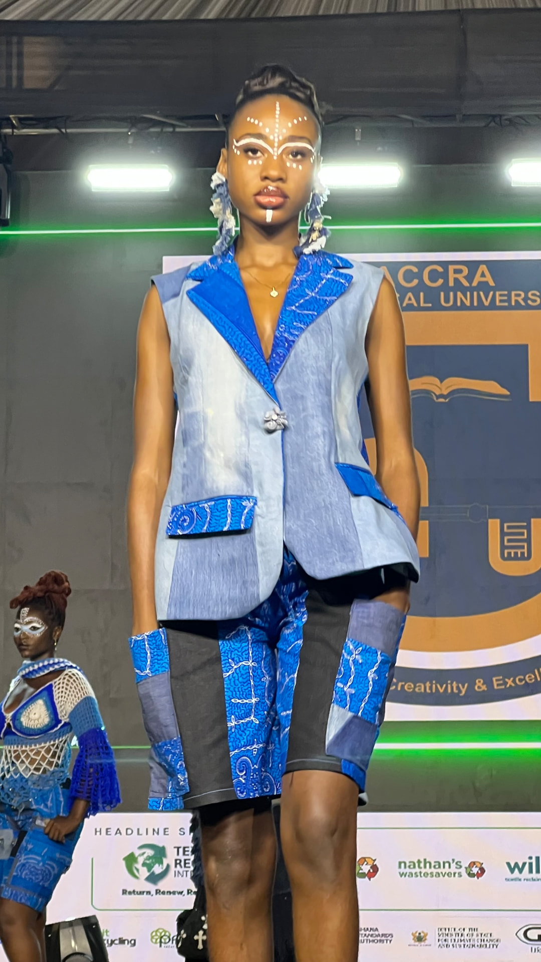 Model on the L2L Summit runway wearing a patchwork denim and adire waistcoat with matching shorts.
