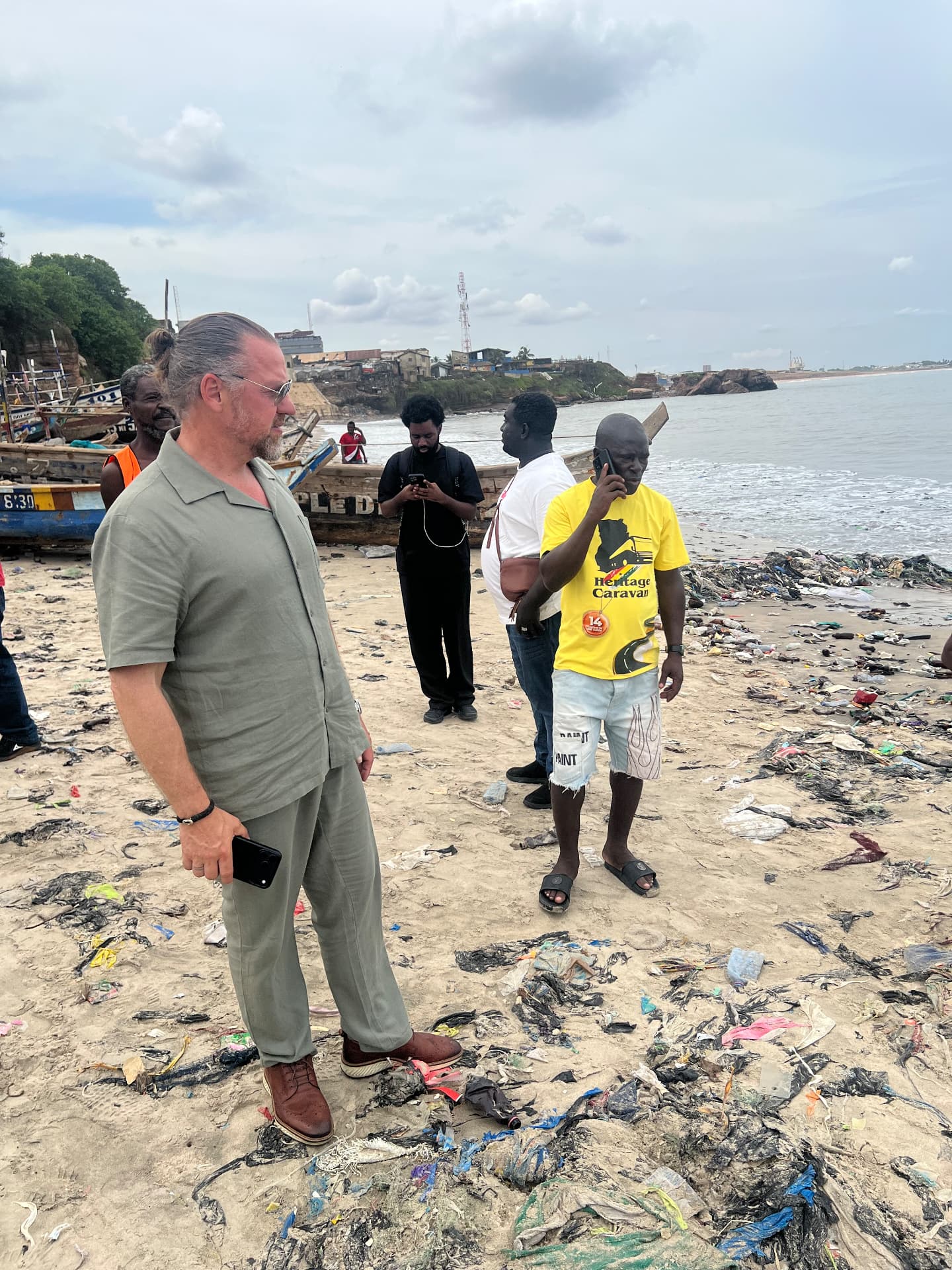 Symolem team on a beach in Accra strewn with textile and plastic waste, speaking with local fishermen.