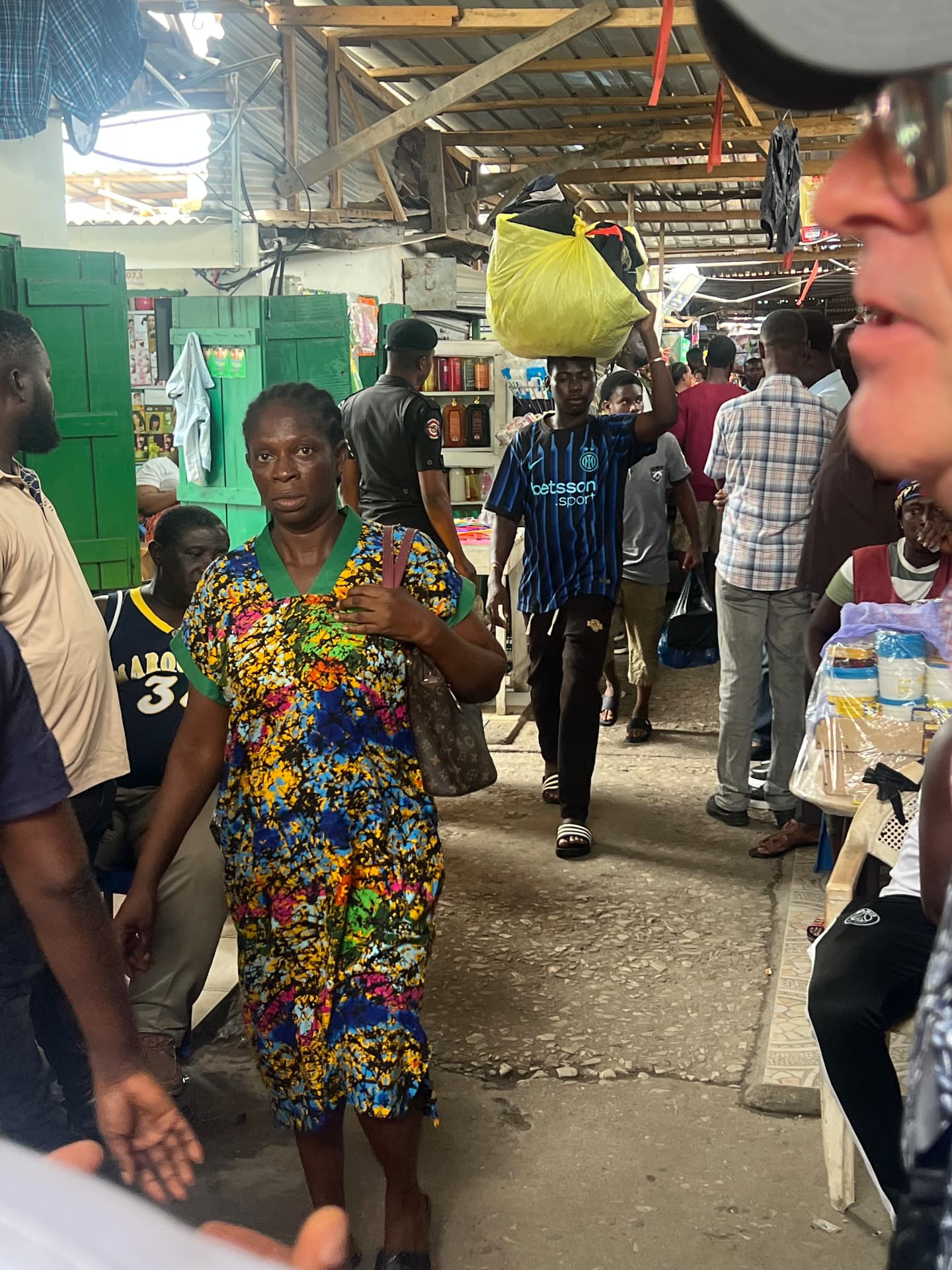 Traders and porters moving through a covered aisle inside Kantamanto Market.
