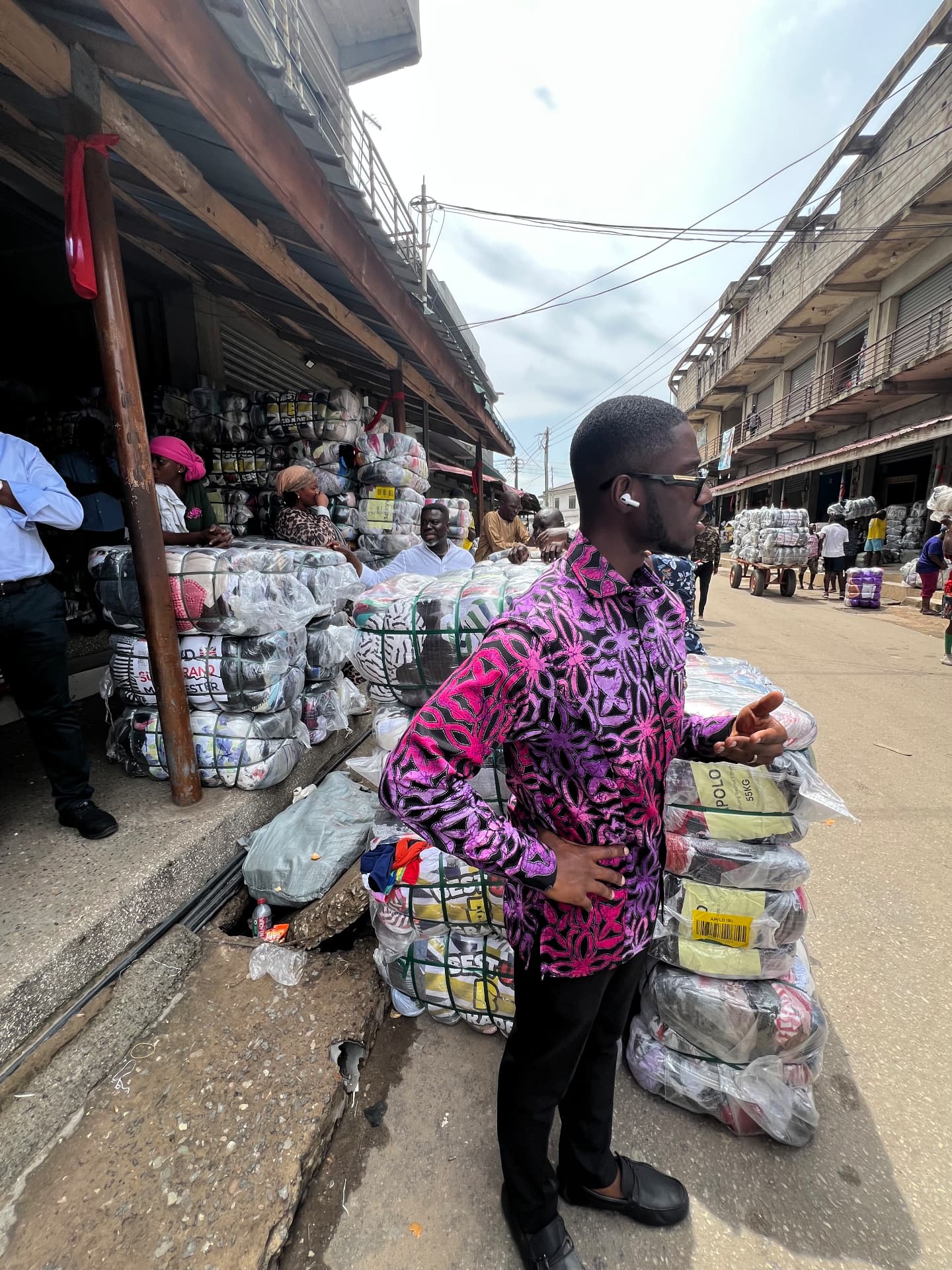 Wholesale bales of imported second-hand clothing stacked on a Kantamanto street.