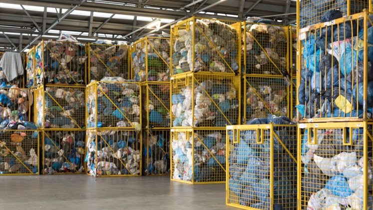 Yellow metal cages stacked in a warehouse, filled with baled textile waste
