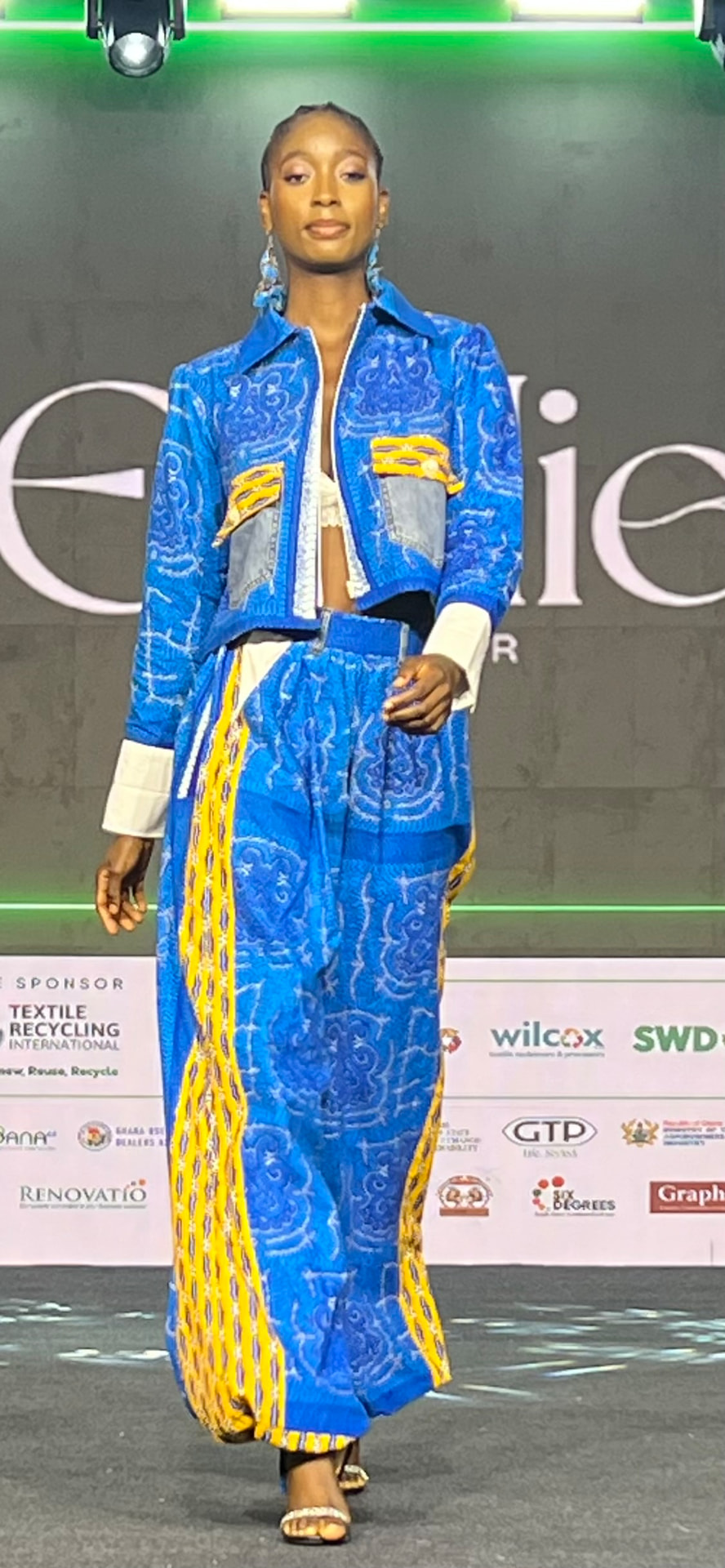Model on the L2L Summit runway wearing a blue and yellow ensemble made from reclaimed textiles.